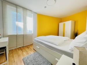 a bedroom with yellow walls and a bed with a desk at Topmodernes Sonnenwohnen Apartment bei U-Bahn und Therme Wien Oberlaa, 15 min bis Stephansplatz in Vienna