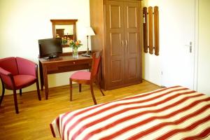 Zimmer mit einem Schreibtisch, einem Bett und einem Stuhl in der Unterkunft Hotel Störtebeker in Graal-Müritz