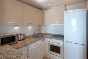 La cuisine est équipée de placards blancs et d'un réfrigérateur blanc. dans l'établissement Apartamento vista mar frontal garaje y WiFi, à Torrox Costa