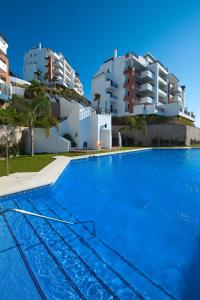 a swimming pool with two apartment buildings in the background at Apartamento vista mar frontal garaje y WiFi in Torrox Costa