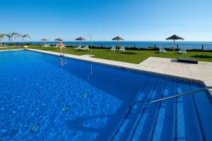 uma grande piscina azul com o oceano ao fundo em Fantástico apartamento de 1 dormitorio frente al mar em Torrox Costa