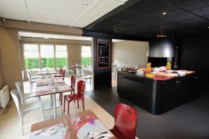 a restaurant with red chairs and tables and a kitchen at Campanile Pont-à-Mousson in Pont-à-Mousson