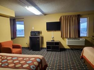 a hotel room with a bed and a flat screen tv at Super 8 by Wyndham Henderson North East Denver in Henderson