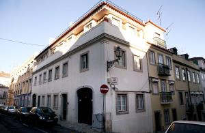 un edificio blanco en una calle con coches aparcados en Triplex - Quarto com w.c. privado, en Lisboa