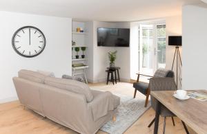 un soggiorno con divano e orologio sul muro di The Burrow by Harrogate Serviced Apartments a Harrogate