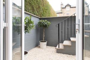 une porte ouverte avec des plantes en pot à côté d'un escalier dans l'établissement The Burrow by Harrogate Serviced Apartments, à Harrogate