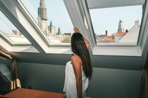 a woman looking out of a window at the city at Hotel 'T Sandt in Antwerp