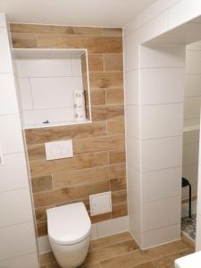 La salle de bains est pourvue de toilettes blanches et de murs en bois. dans l'établissement Kunstgasse 4+5, à Altenburg