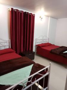 two beds in a room with red curtains at Rani Homestay in Cherrapunji