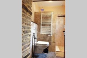 a bathroom with a toilet and a stone wall at La Dolce Vita des Hautes Côtes in Magny-lès-Villers
