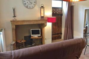 a living room with a couch and a fireplace with a clock at La Dolce Vita des Hautes Côtes in Magny-lès-Villers