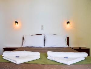 a bed with two white towels on top of it at Panorama Hotel in Falasarna