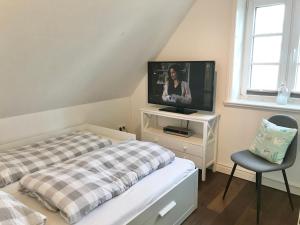 Schlafzimmer mit einem Bett, einem TV und einem Stuhl in der Unterkunft Deichhof Knudsen in Oldsum