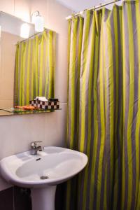 a bathroom with a sink and a green shower curtain at Panorama Hotel in Falasarna