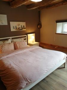 a bedroom with a large bed with pink sheets at Gîte Le Courtil in Bouillon