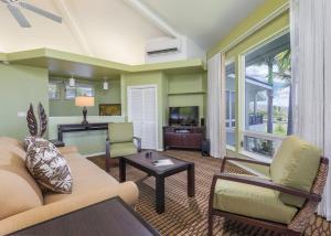 a living room with a couch and chairs and a tv at Holua Resort in Kailua-Kona