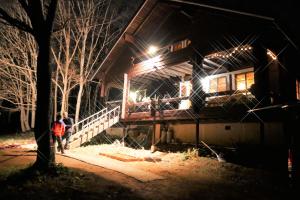 una persona de pie delante de una casa por la noche en Niseko FOREST VILLA en Niseko