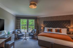 a hotel room with a bed and a desk and chair at Cuillin Hills Hotel in Portree
