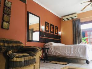 una camera da letto con un letto, uno specchio e una sedia di Mopani Guest House a Giyani