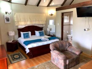 a bedroom with a large bed and a chair at Gaggle Inn Guest Lodge in Kroonstad