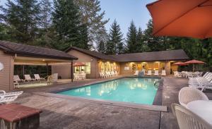 Welches的住宿－Whispering Woods Resort, a VRI resort，一个带椅子的游泳池以及一座房子