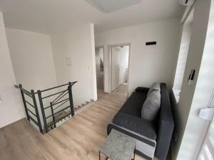 sala de estar con sofá negro y mesa en Hajnal Apartmanház, en Hajdúszoboszló