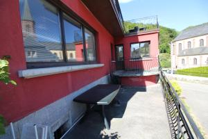 un banc assis sur le côté d'un bâtiment rouge dans l'établissement Gîte Lion d'Or, à Le Bonhomme 3 autres photos