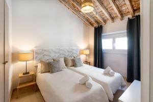 1 dormitorio con 2 camas blancas y ventana en Apartamentos Juan de Padilla, en Málaga
