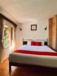 a bedroom with a bed with red pillows and a window at Hotel De Cervantes in San Sebastián