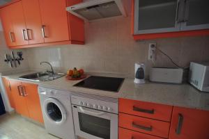 a kitchen with orange cabinets and a stove and a sink at Casa Paradiso with great views perfect for surf or family holidays in Famara