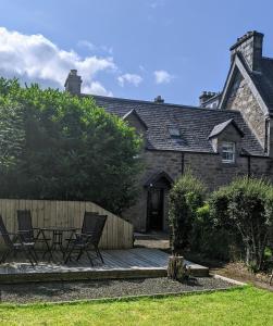 Casa con 2 sillas y terraza de madera en Kinloch Rannoch Holiday Cottage en Kinloch Rannoch