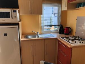 a small kitchen with a sink and a microwave at FLAMANTS ROSES 1 pers 6 in Frontignan