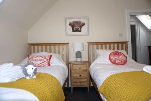 a bedroom with two beds and a stuffed cow on the bed at Kinloch Rannoch Holiday Cottage in Kinloch Rannoch