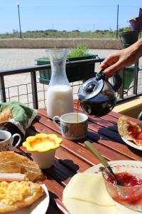 a table topped with plates of food and a jug of milk at Abrigo das Nortadas in Vila do Bispo