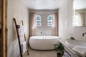 a white bathroom with a large tub and a sink at visitHOMES Faroe Islands in Leirvík