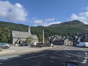 a small town with a church and a street at Kinloch Rannoch Holiday Cottage in Kinloch Rannoch