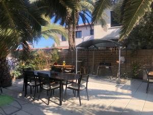 un patio con mesa, sillas y sombrilla en FLAMANTS ROSES 2 en Frontignan