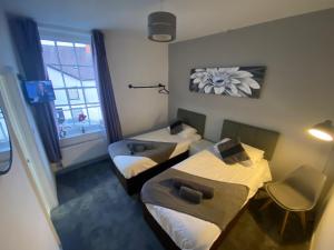金顿The Swan Hotel的有两张床和一扇窗户的小房间