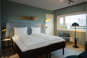 Un dormitorio con una gran cama blanca y una ventana en Scandic Helsfyr en Oslo