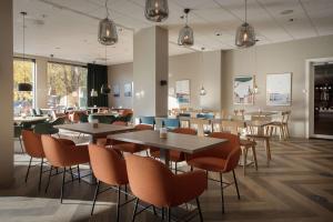 uma sala de jantar com mesas, cadeiras e janelas em Scandic Helsfyr em Oslo