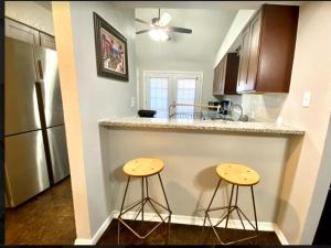 una cocina con 2 taburetes en una barra con nevera en Private Bedroom Suite - Communal House near Integris, en Oklahoma City
