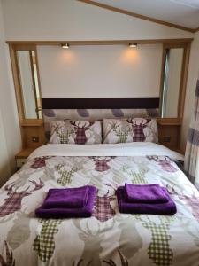 a bed with purple pillows on top of it at Deer lodge in Auchterarder
