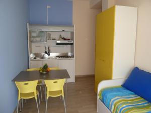 Cette chambre comprend une petite cuisine avec une table et des chaises jaunes. dans l'établissement Silvi Marina Sea Resort, à Silvi Marina