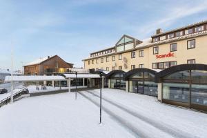 een gebouw met een met sneeuw overdekte parkeerplaats ervoor bij Scandic Vadsø in Vadsø