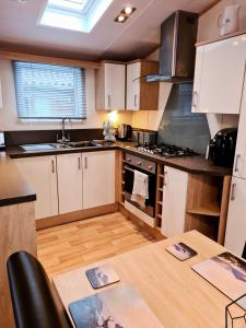 a kitchen with white cabinets and a wooden table at Deer lodge in Auchterarder