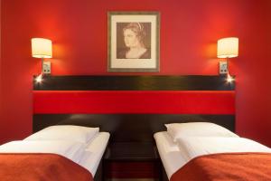 two beds in a room with red walls at Scandic Holberg in Oslo