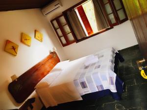 a bedroom with a bed and two windows at Pousada Azul Banana - Camburi in Camburi