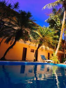 a resort with palm trees and a swimming pool at Pousada Azul Banana - Camburi in Camburi