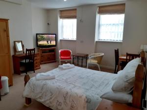 a bedroom with a bed and a tv and chairs at The Edenhurst Guesthouse in Weymouth