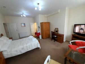 a bedroom with a bed and a desk and a television at The Edenhurst Guesthouse in Weymouth